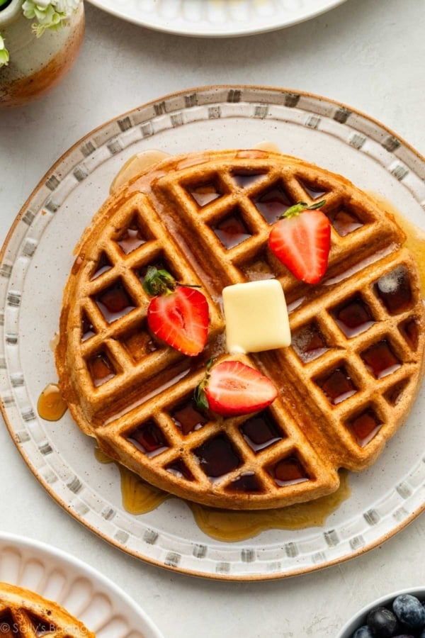 whole wheat waffle with strawberries and butter on top.